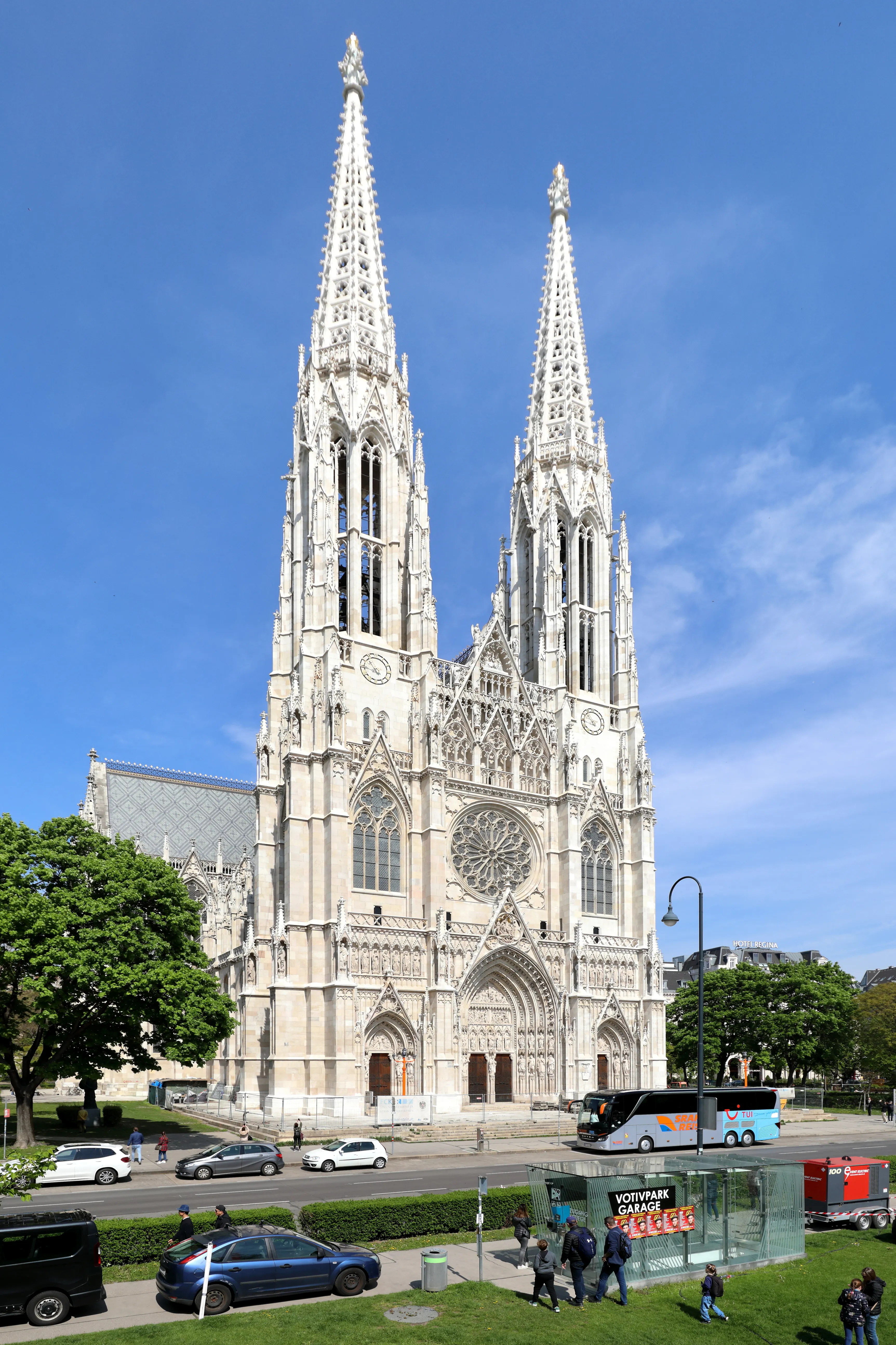 Neo-Gothic church with twin spires and a large rose window under a blue sky