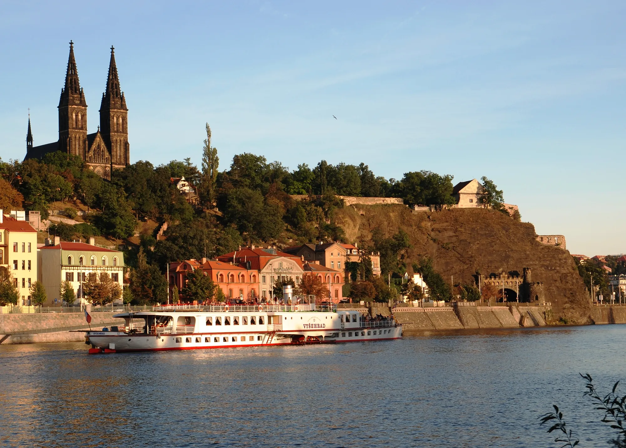 Un crucero fluvial en el río Moldava con la fortaleza de Vyšehrad y su basílica de doble aguja al fondo.