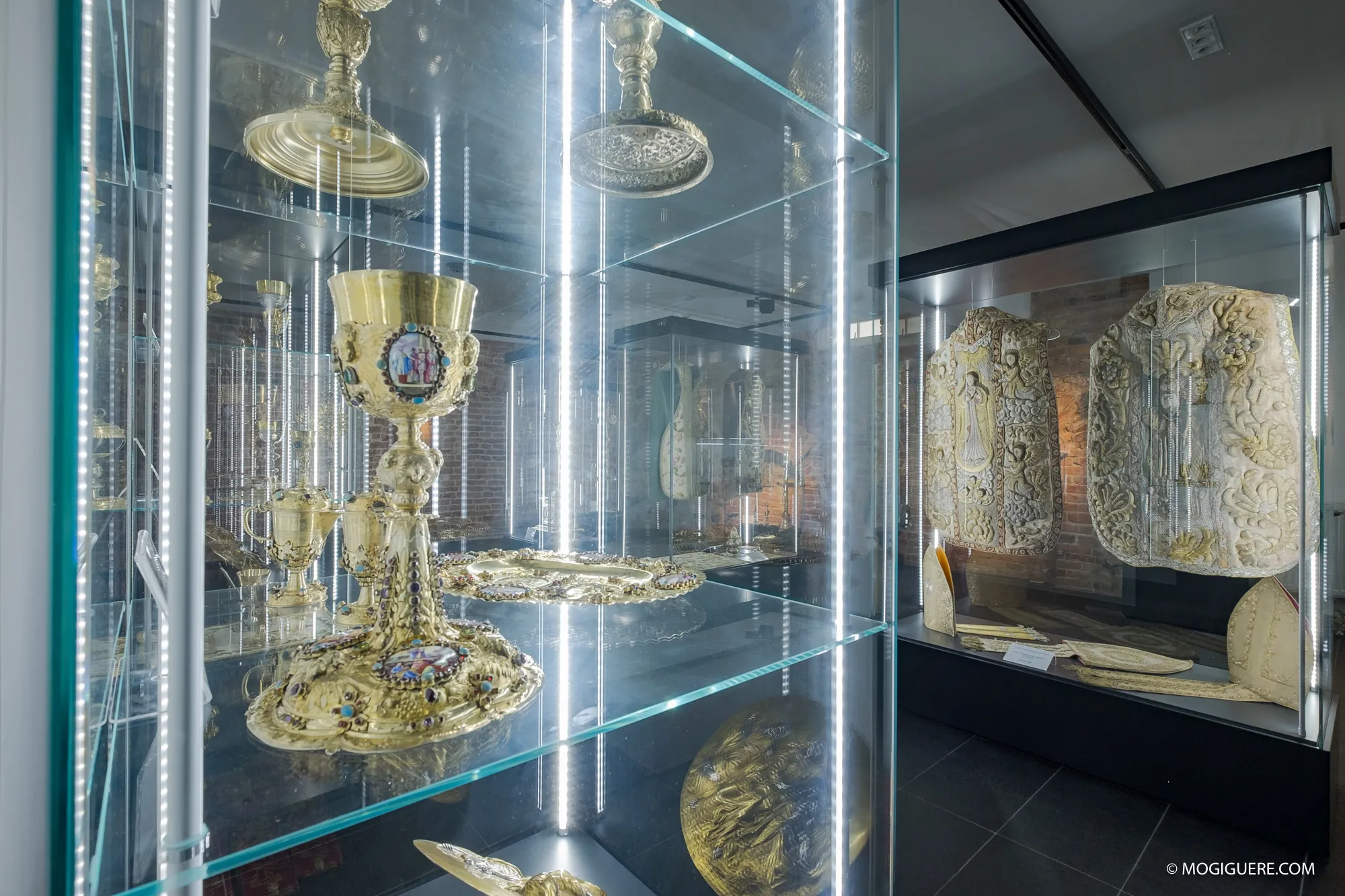 In glazen vitrines liggen gouden kelken en stenen reliëfs in een museumzaal.