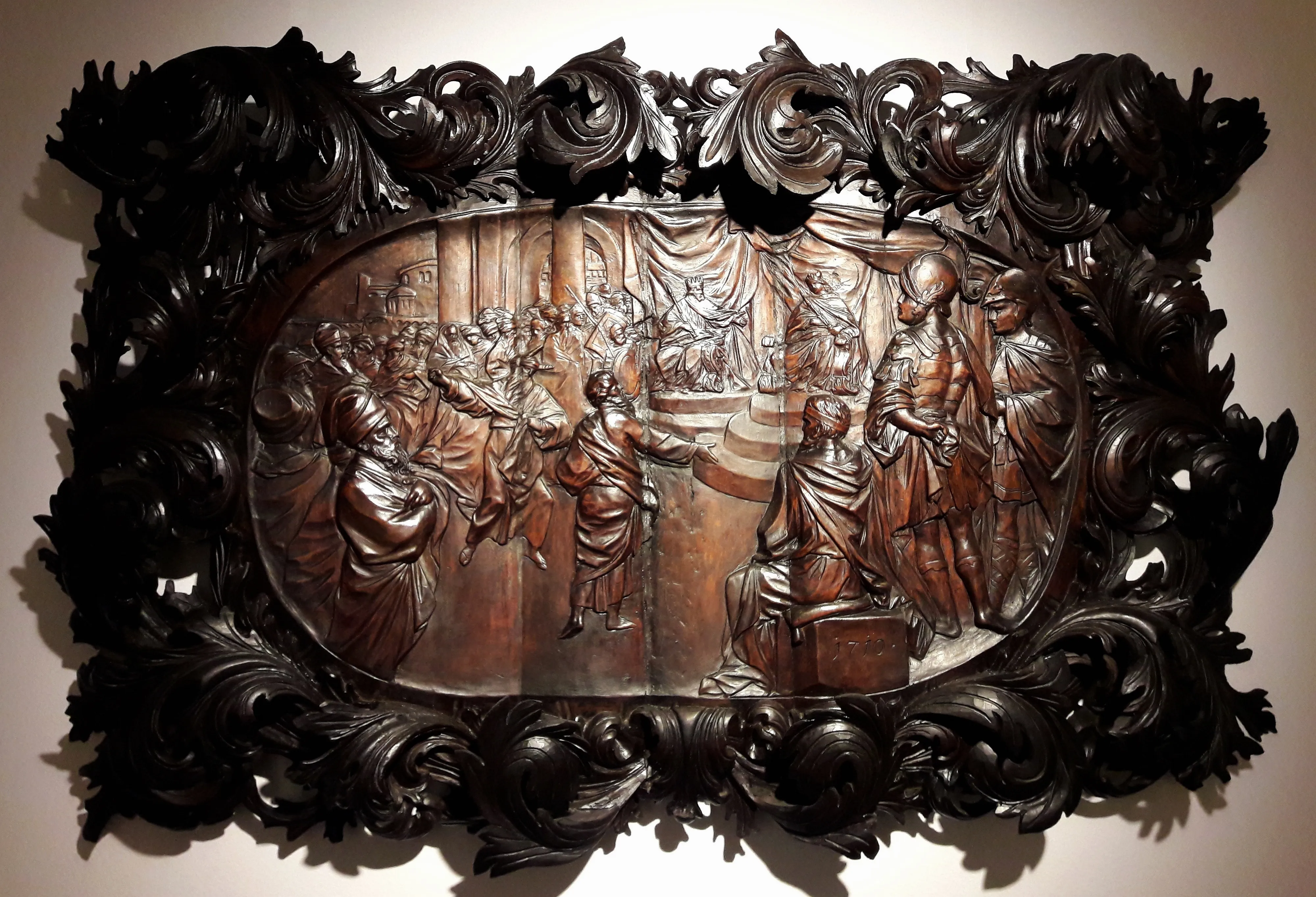 houten reliëfsculptuur met sierlijk frame dat figuren toont in een Bijbelse scène