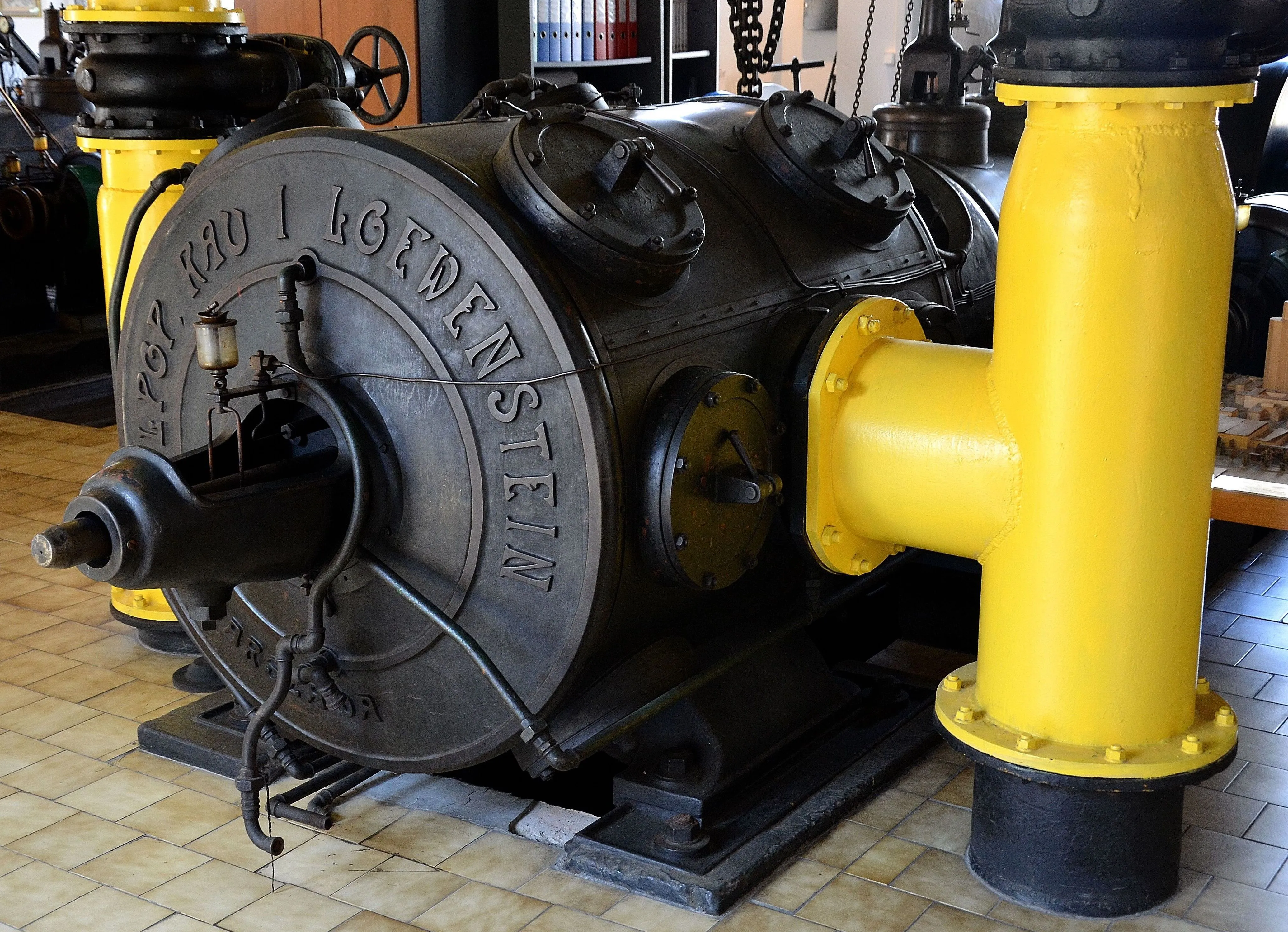 Large industrial gas compressor with engraved text and yellow pipe connection