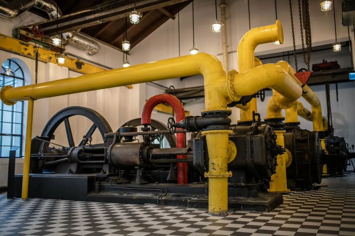 Industrial engine with yellow and red pipes on display in a museum