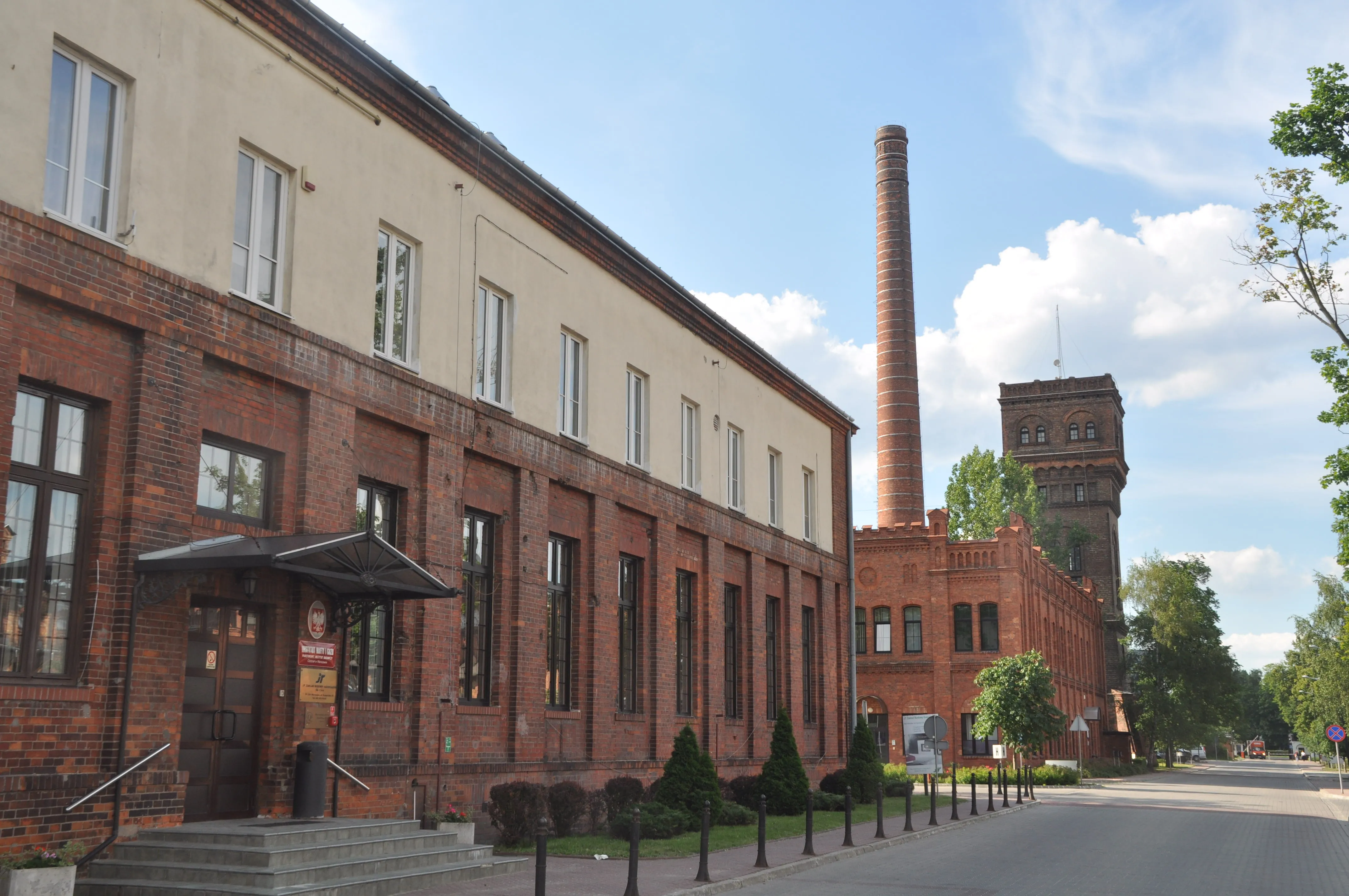 Brick building with a tall chimney and water tower under a blue sky