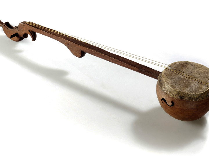 Wooden string instrument with long neck, round body, and decorative headstock against white background
