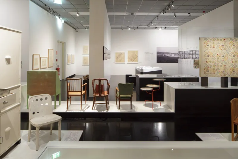 nowoczesne meble i designerskie przedmioty wystawione w galerii z białymi ścianami i czarną podłogą