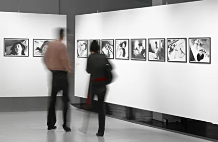 Two people viewing framed photographs on display in a museum gallery