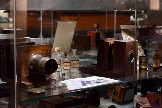 vintage cameras and photographic equipment displayed in a glass case