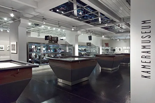 Interior of the WestLicht Camera Museum with display cases and a sign reading KAMERAMUSEUM on the wall