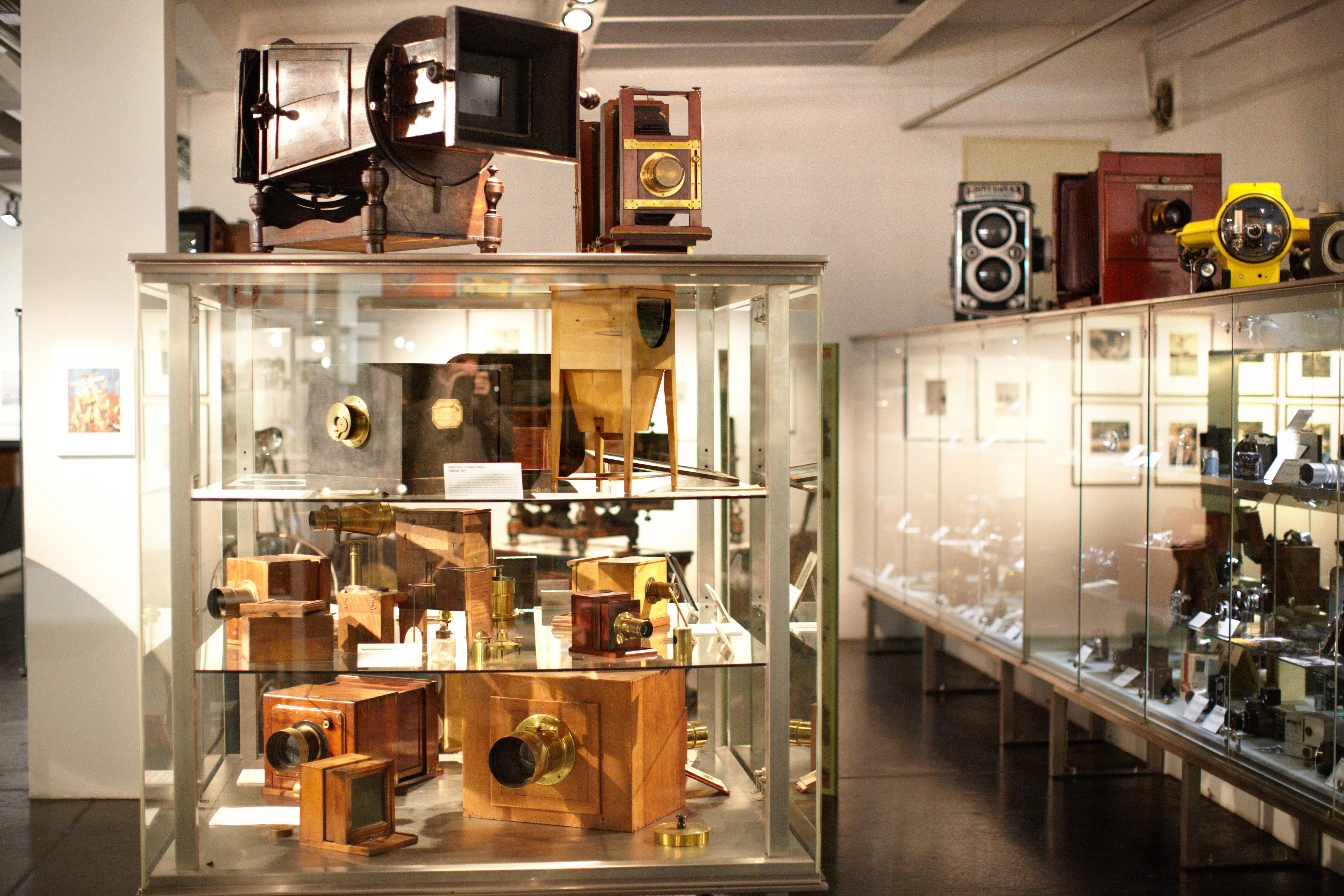 Glass display case filled with historic cameras and photographic equipment in a museum gallery