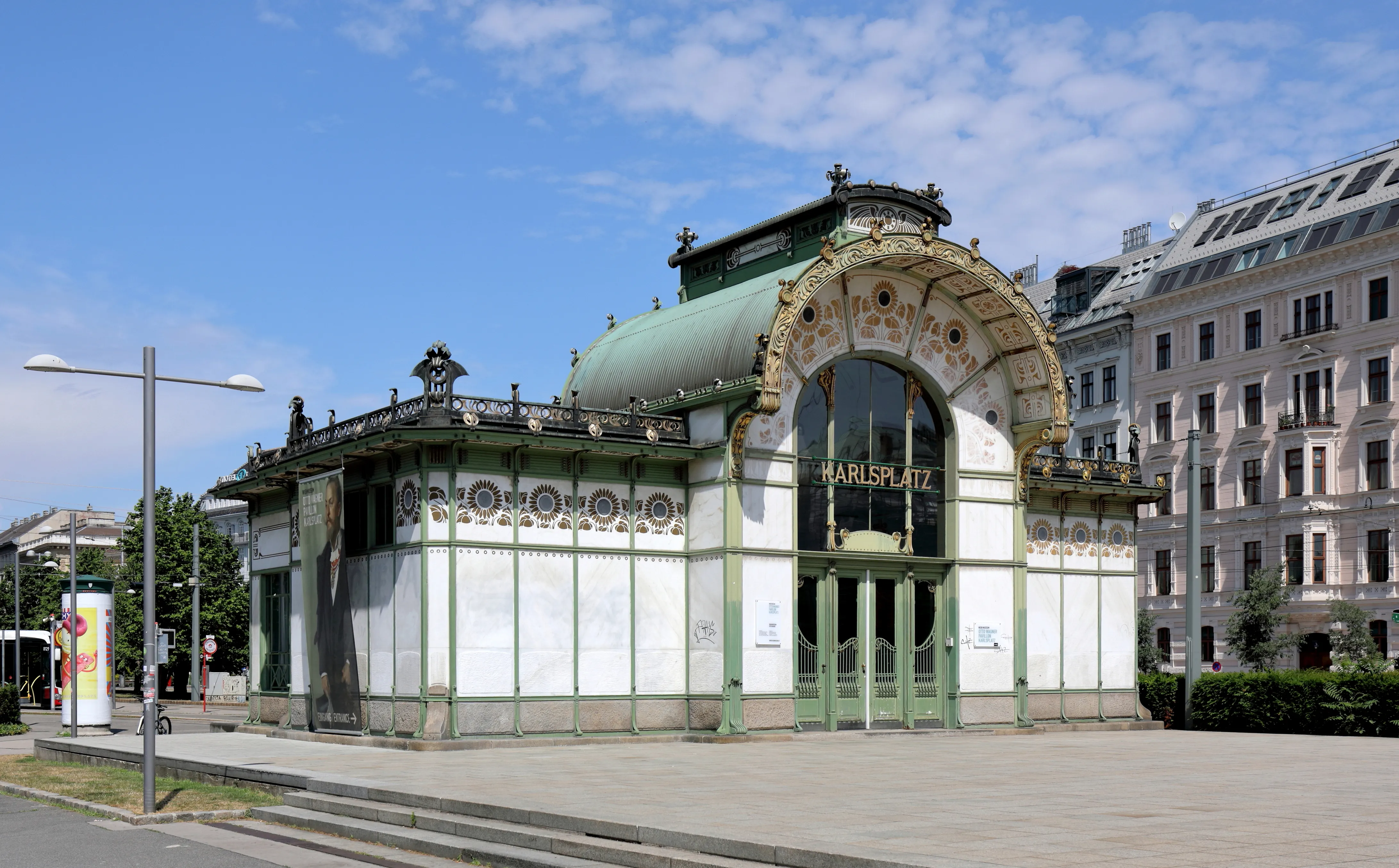 Het Otto Wagner Paviljoen op Karlsplatz met een groen-witte gevel, gebogen glas-in-loodramen en sierlijke architectonische details onder een blauwe hemel.