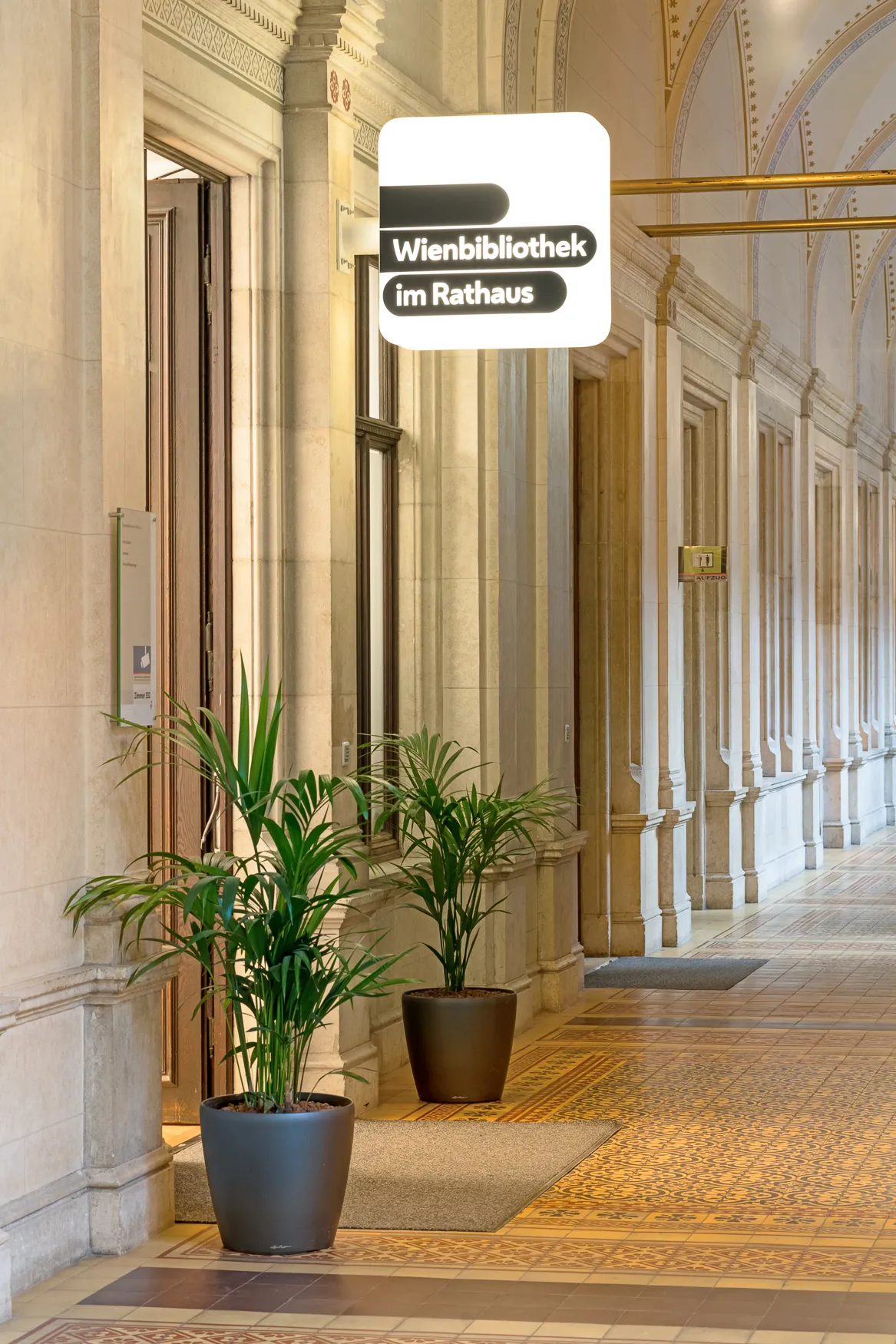 Hol wejściowy Wienbibliothek im Rathaus ze znakiem, kolumnami i roślinami doniczkowymi