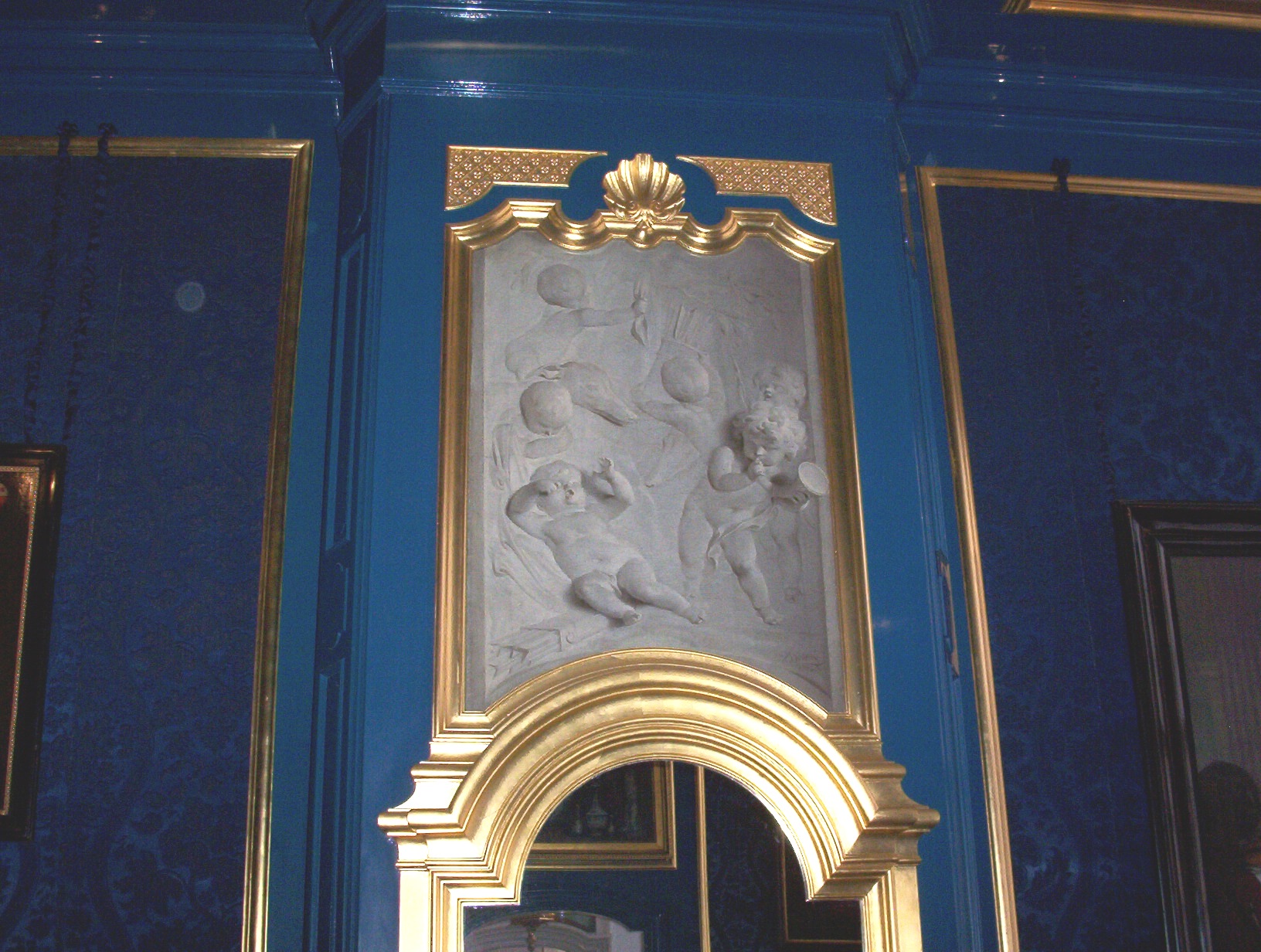White marble relief sculpture in a gold frame on a blue wall