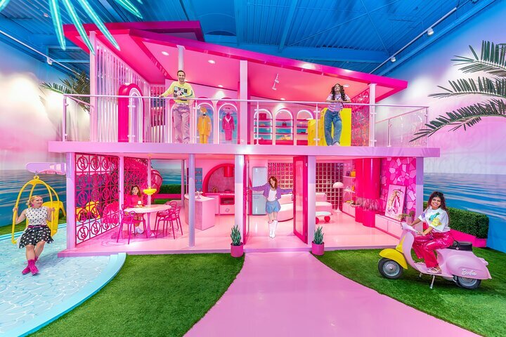 Vibrant pink two-story installation with people exploring colorful rooms and playful elements at WONDR Experience