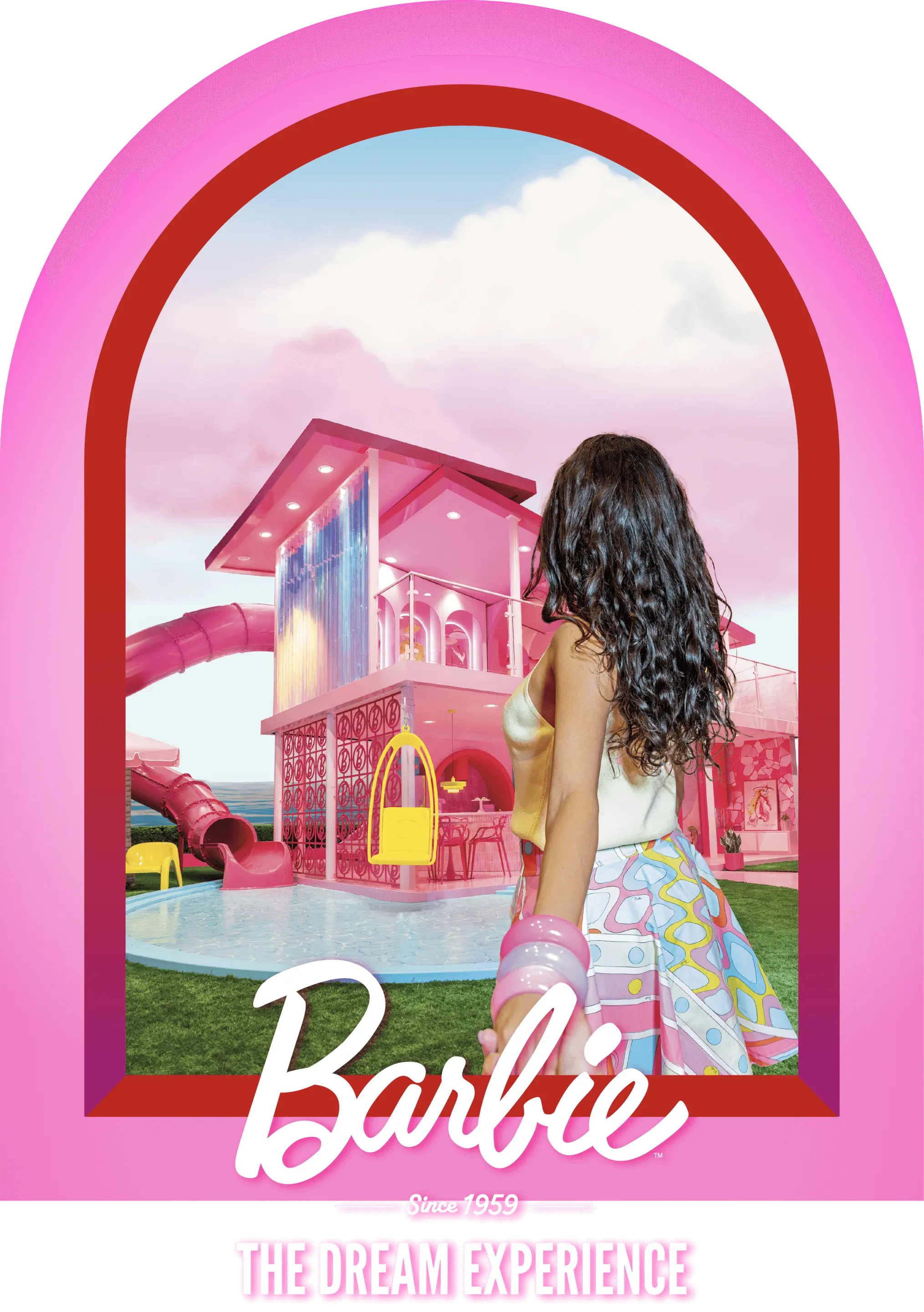 Barbie-themed installation with pink archway framing a pastel-colored house, pool, and slide, viewed by a woman with curly hair.