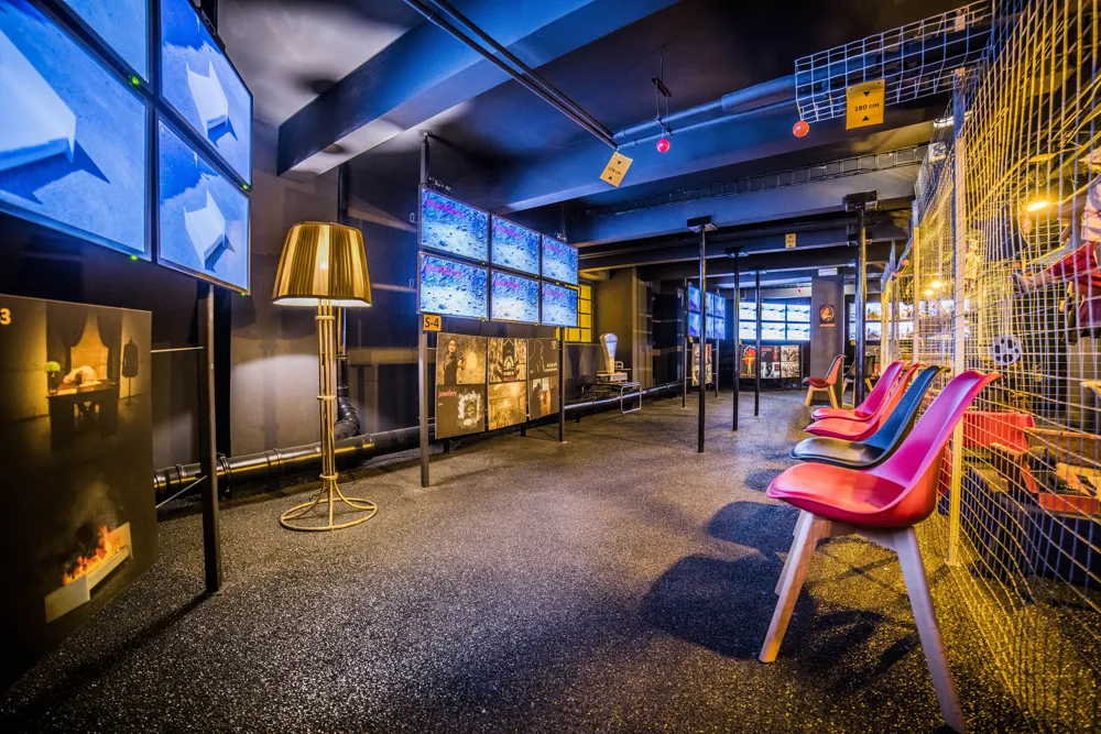 Interior of the World of Franz Kafka with blue-lit screens, a gold lamp, and colorful chairs