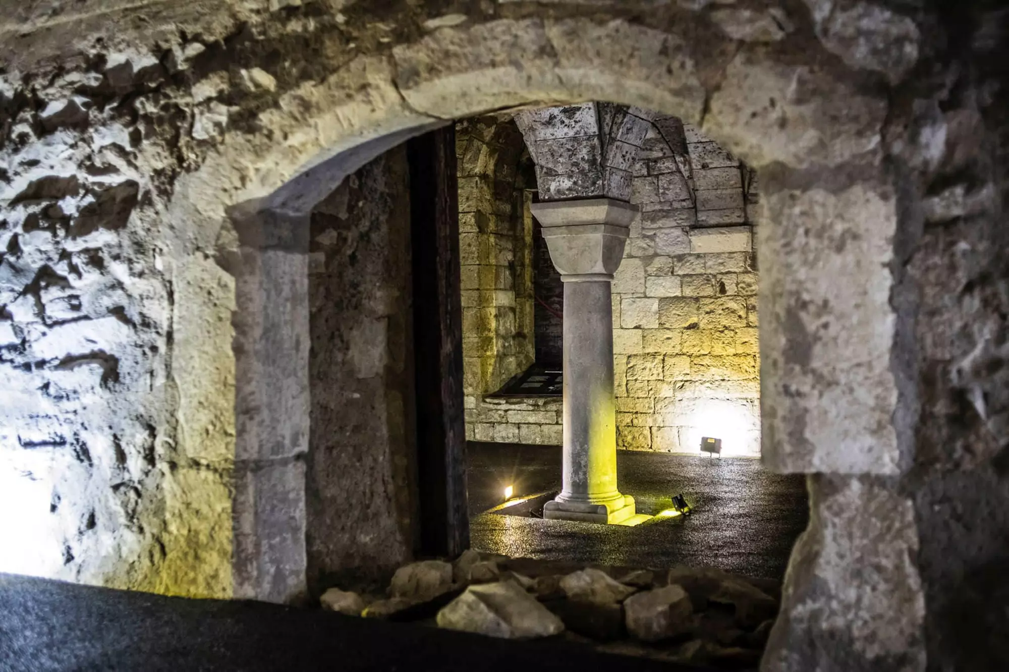 stone archway leading to a dimly lit chamber with a central column and stone walls