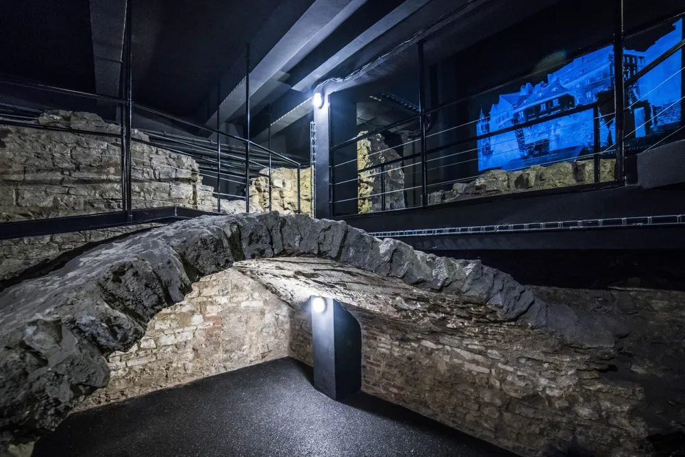 stone archway in a dimly lit interior space with a projection on a screen