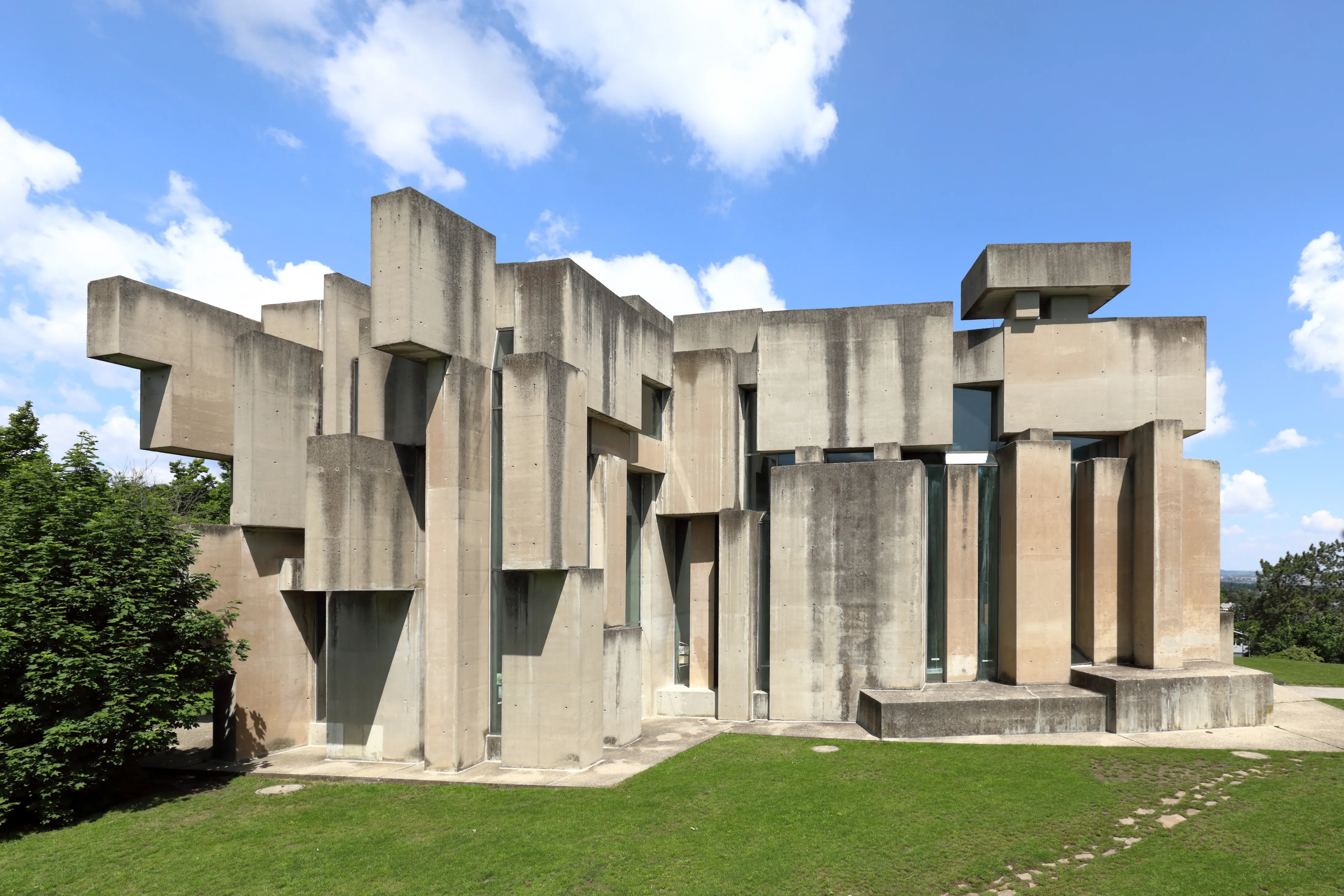 Modern betonnen kerkgebouw met geometrische blokstructuren onder een blauwe hemel