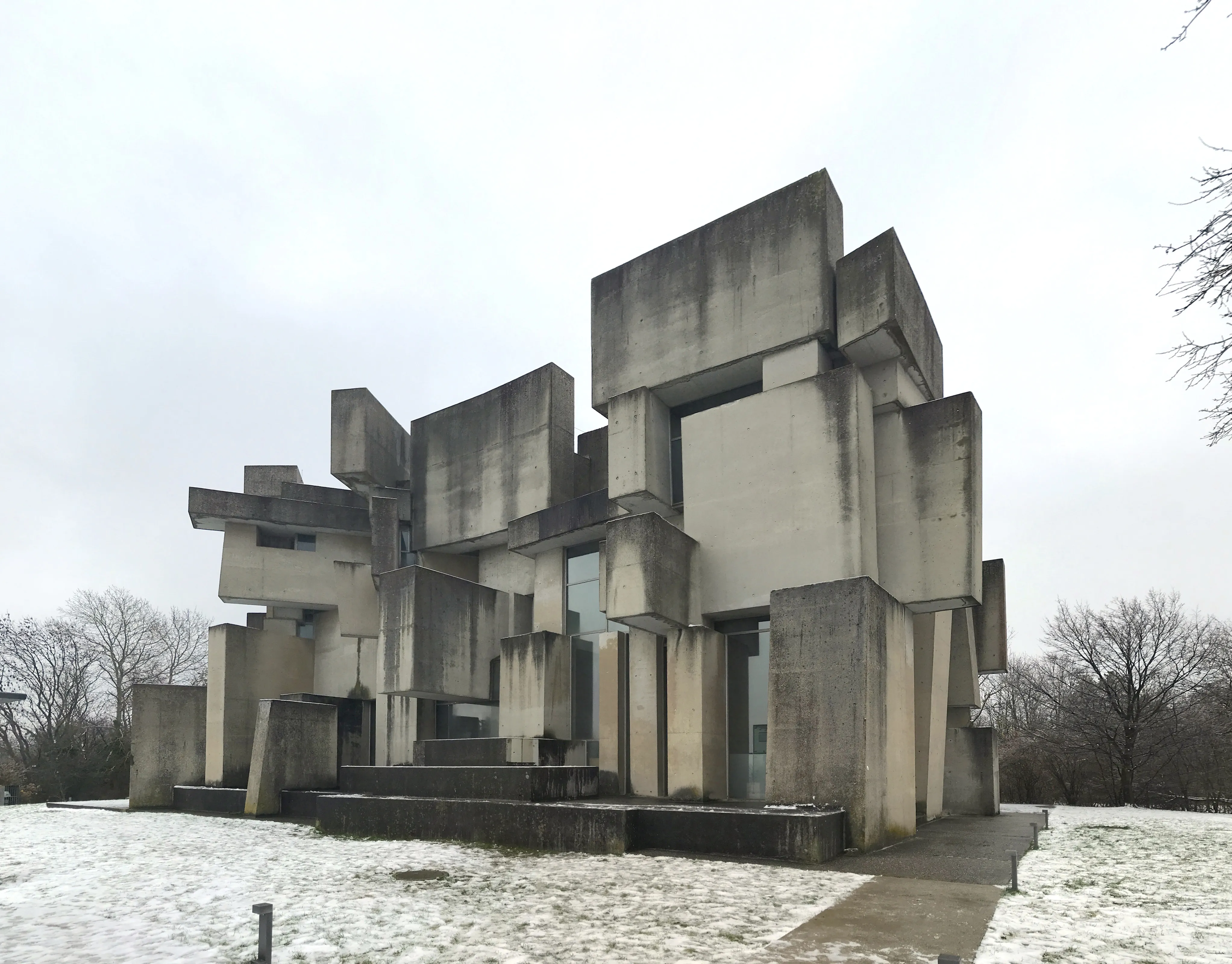 Modern betonnen kerkgebouw met geometrische blokken en sneeuw op de grond