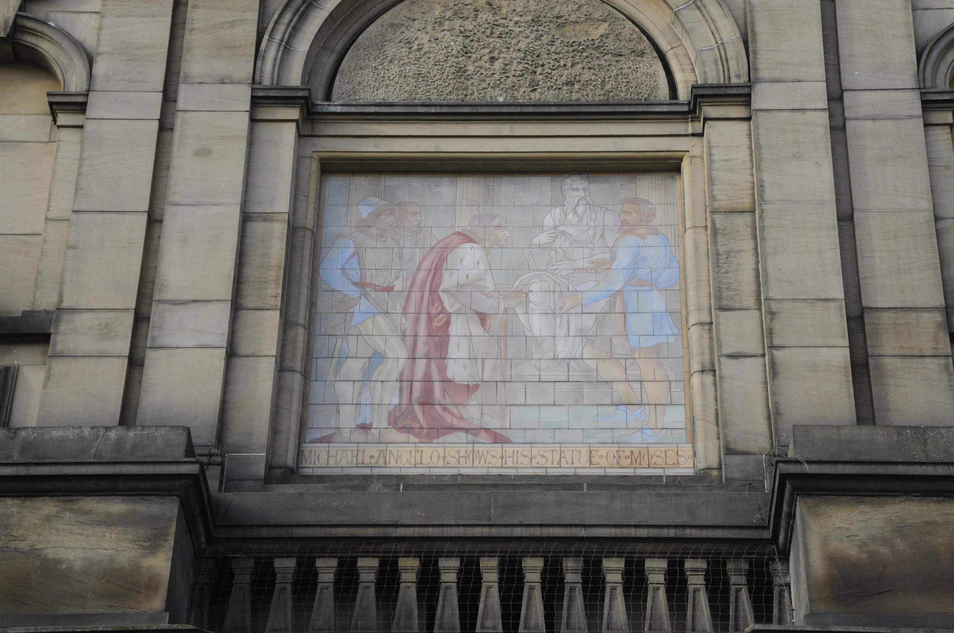 Mozaikowy panel na kamiennej fasadzie York Art Gallery przedstawiający postacie w historycznych strojach pod łukowatym oknem