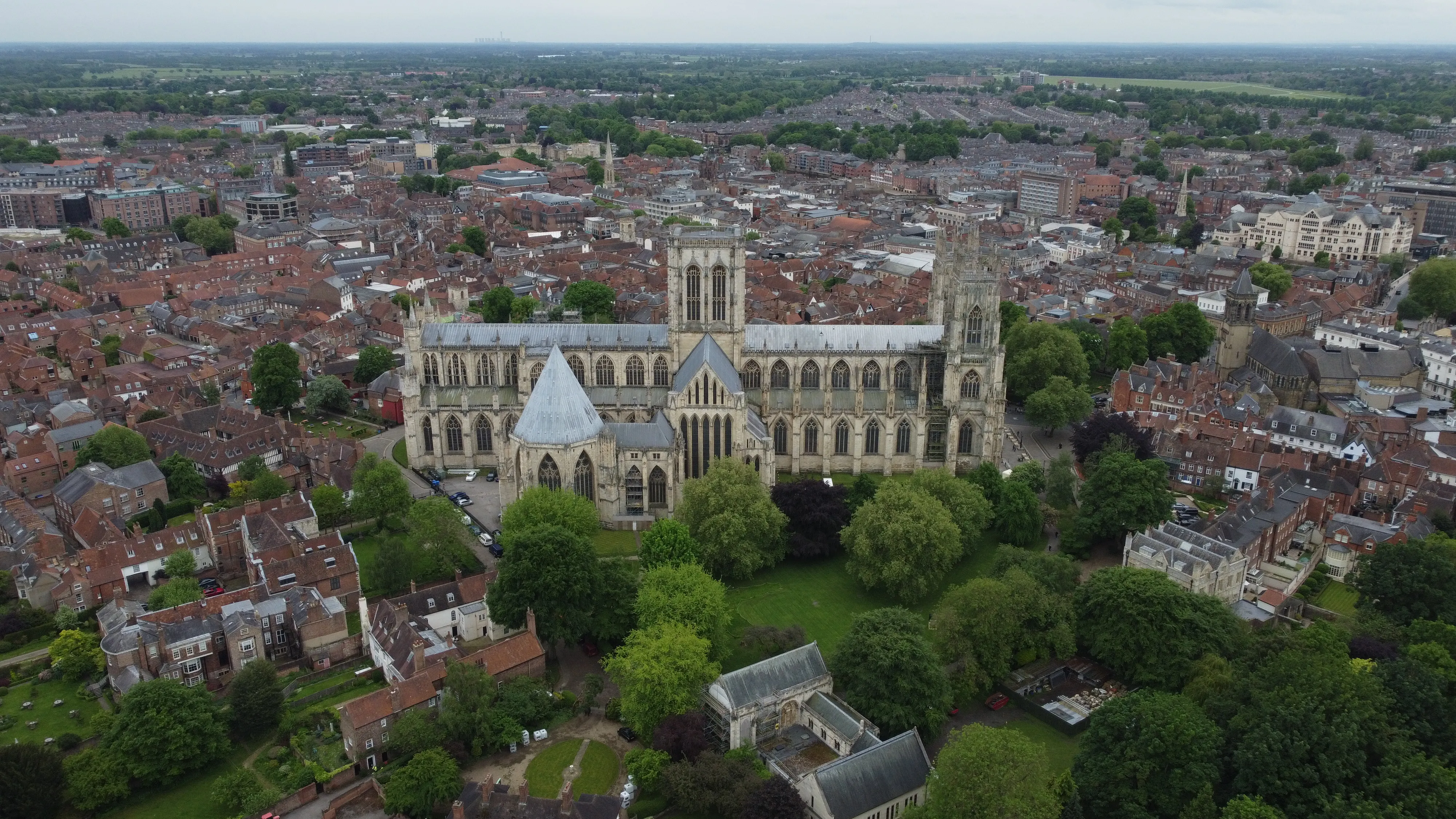 Aerial view of York Minster cathedral surrounded by the city's red-roofed buildings and green trees.