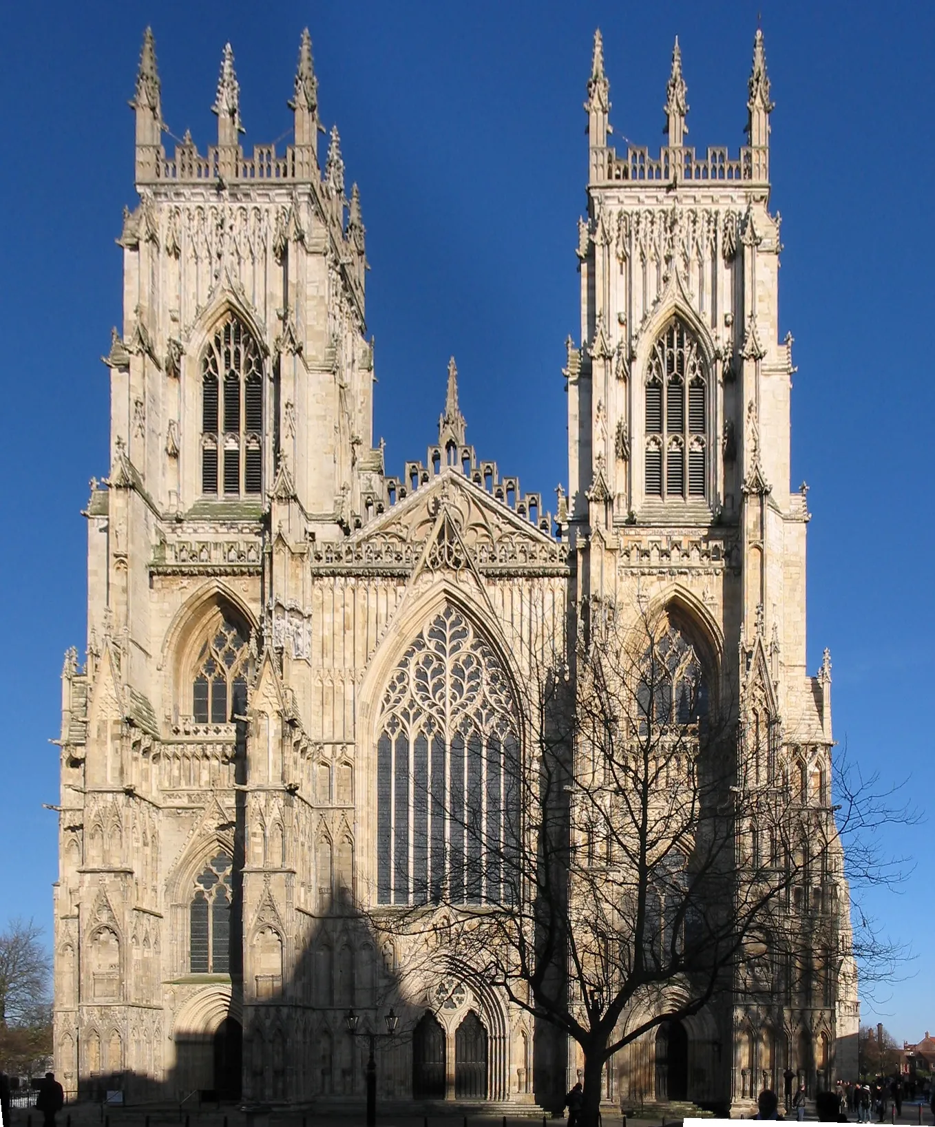 West front facade of York Minster showing two Gothic towers, the great west window, and intricate stonework against a clear blue sky