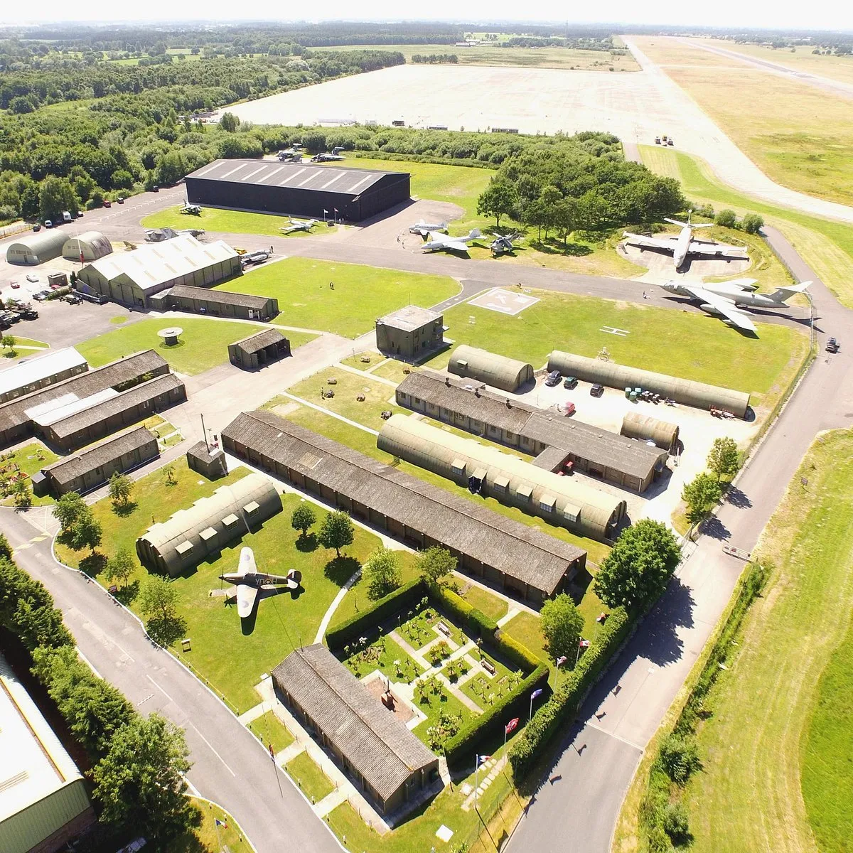 Luchtfoto van het terrein van het Yorkshire Air Museum met historische vliegtuigen, hangars, Nissenhutten en een start- en landingsbaan op de achtergrond.
