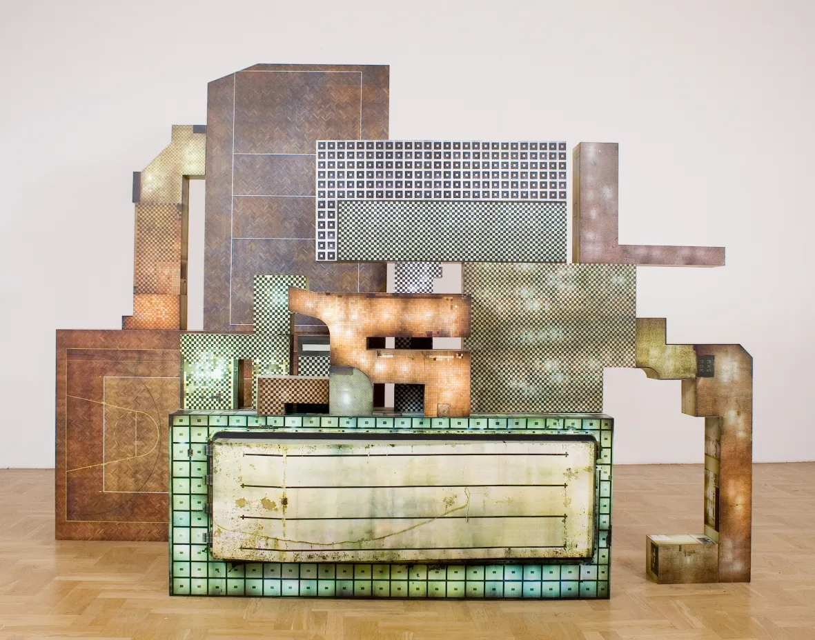 Escultura abstracta con formas geométricas y materiales mixtos en un entorno de galería