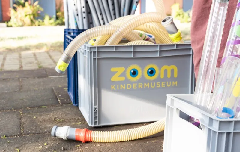 szara skrzynia do przechowywania z logo ZOOM KINDERMUSEUM i elastycznymi rurkami